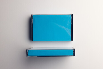 Overhead view of two blue cassette tape boxes arranged on white background