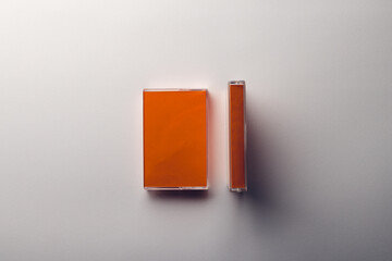Overhead view of two orange cassette tape boxes with copy space arranged on white background