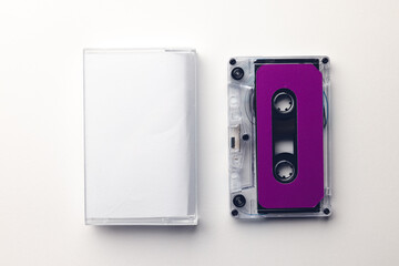 Overhead view of purple cassette tape and white box arranged on white background