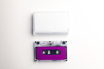 Overhead view of purple cassette tape and white box arranged on white background