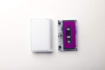 Overhead view of purple cassette tape and white box arranged on white background