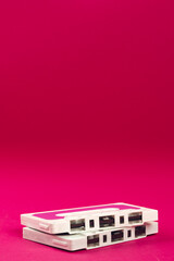 Close up of pink and white cassette tapes with copy space on pink background