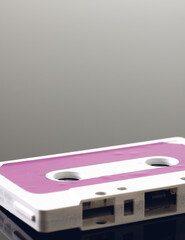 Close up of white and pink cassette tape with copy space on grey background with reflection