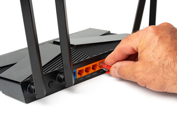 Man's hand plugging internet cable into wifi router