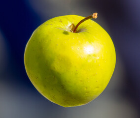 A green apple hangs in the air