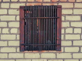Rusty metal bars on a window on a brick wall