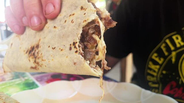 tourist eating traditional mexican food tortillas or tlayudas filled with meat