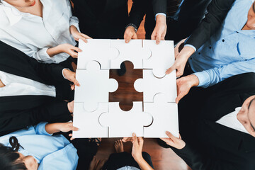 Top view multiethnic business people holding jigsaw pieces and merge them together as effective...