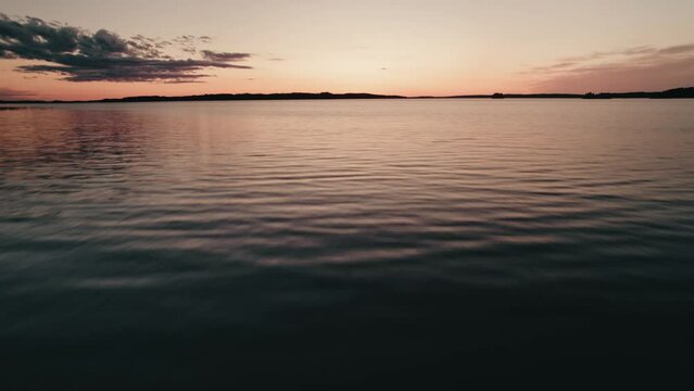 Drone flying low and fast over water at sunset, Finland, lake saimaa