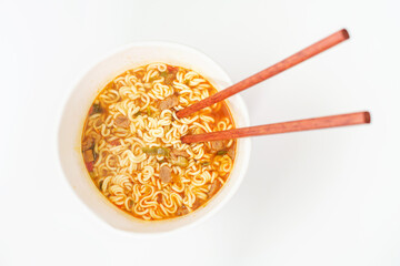 A bowl with ready ramen and wooden sticks on white background, top view.