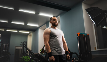 Fototapeta na wymiar A man with a beard is a weightlifter preparing to do exercises in the gym. A heavy, purposeful look.