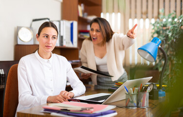 Irritated woman boss scolding stressed manager for incompetence with documents in office
