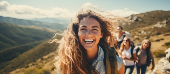 A group of happy friends embarked on an adventurous mountain hike, enjoying the carefree summer sky and breathtaking views from the hilltop, while having fun and creating lifelong memories. Among them
