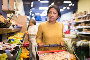 Casual woman doing shopping in grocery department of supermarket