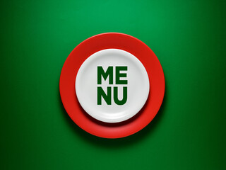 The word Menu on ceramic white plate over green background. Restaurant or cafe menu design concept.