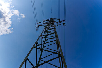 Looking up pylon of high voltage power line in bright sunlight on a hot summer day at City of Zürich district Schwamendingen. Photo taken July 10th, 2023, Zurich, Switzerland.