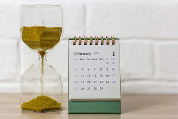 Desk calendar for February 2024 and a clock on the table with copy space.