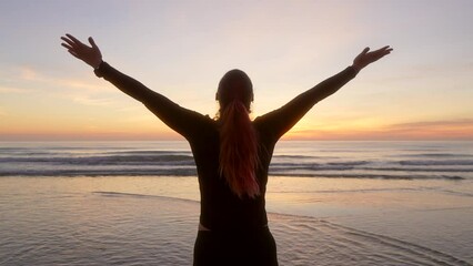 woman spreads her arms and breathes watching the sunrise