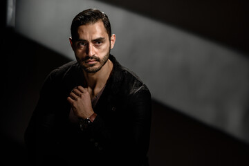 Dramatic portrait of young bearded brutal handsome man on dark background, Powerful dark portrait:...