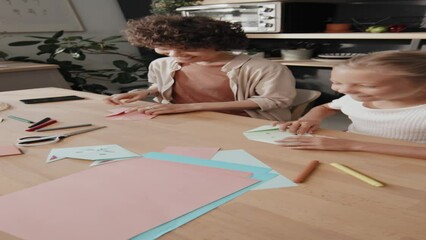 Mom and daughter creating origami figures when dad bringing colored paper to them, they showing him paper toys - Powered by Adobe
