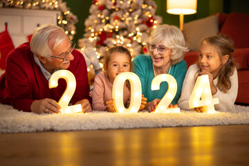 Children celebrating New Year with grandparents holding numbers 2024