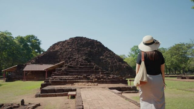 Back view of female tourists walking into ancient architecture at Si Thep historical park new world heritage site in Phetchabun, Thailand. New UNESCO archaeological site in Petchabun Thailand
