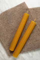 Two homemade beeswax candles onlight marble background. Candles with honey aroma. Cotton wick. Top view, flat lay. 
