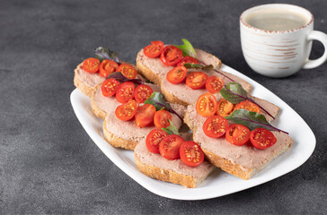 Homemade sandwiches with turkey pate and cherry tomatoes, also a cup of coffee on gray background