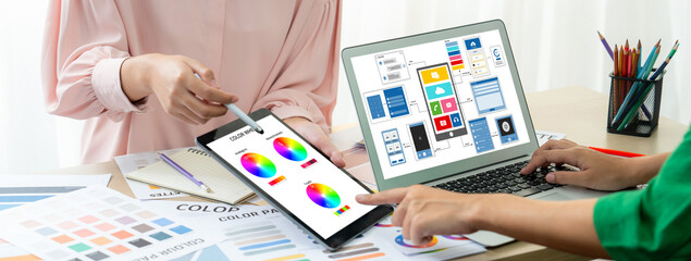 Cropped image of interior designer team presents color by using color palette while laptop displayed UI and UX designs for mobiles app and website. Creative design and business concept. Variegated.