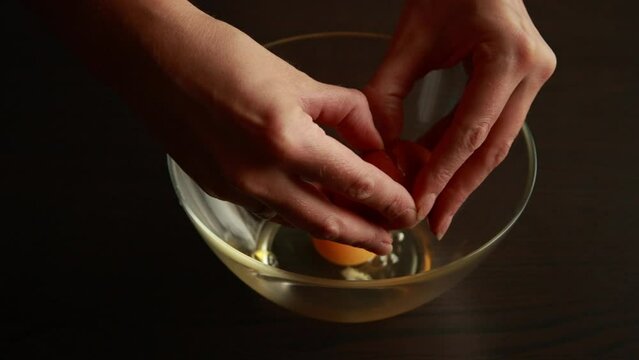 woman's hand cracked and broke the egg into a bowl,slow motion shot.