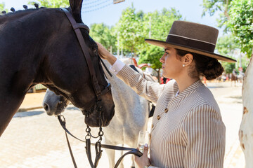 Stylish woman with black horse on ranch during summer