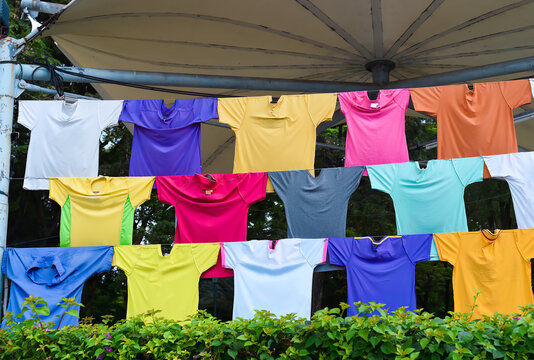 Many colorful different t shirts hanging on ropes