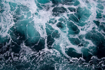 Sea background. The ship's footprint on the water. Waves in the sea. The surface of the sea, bubbling from the screws of the liner. Water foamed by a passing ship. Space for text. Marine texture