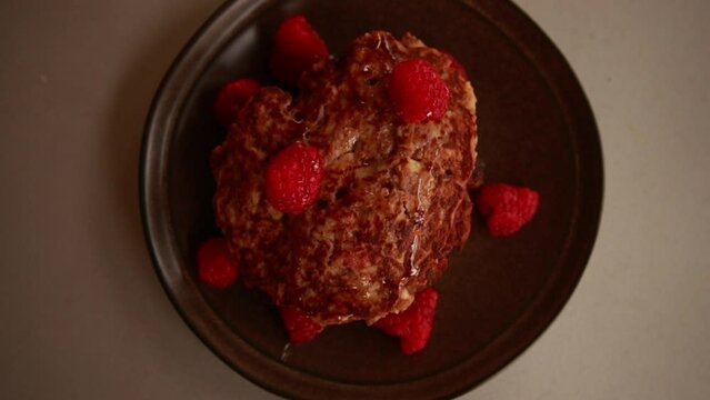 Close-Up of Apple Cinnamon Pancakes with Raspberries and Honey on Table"