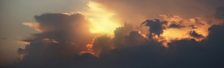 Panoramic aerial view of twilight sky with silhouette storm clouds and golden sunset. Image use for travel destination and meteorology presentation background.