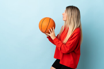 Young blonde woman isolated on blue background playing basketball