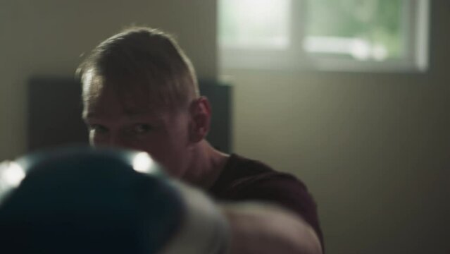 Athlete shows hooks and uppercuts training in sports club. Professional boxer trains punches before camera in gym slow motion. Martial arts exercises