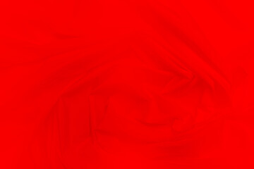 Red textile fabric background, abstract background, luxurious fabric or fluid waves or wavy folds. Creases of satin, silk, and cotton.
