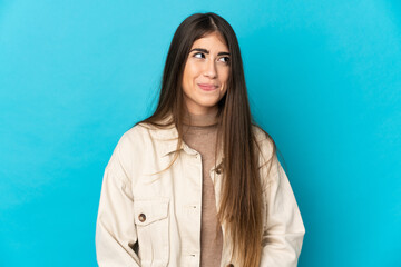 Young caucasian woman isolated on blue background having doubts while looking up