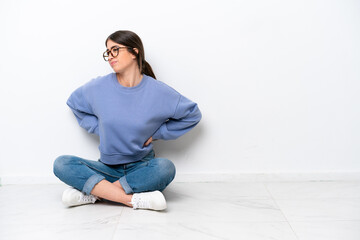 Young caucasian woman sitting on the floor isolated on white background suffering from backache for...