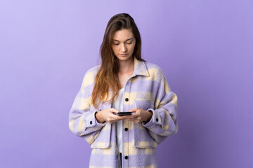 Naklejka premium Young Ireland woman isolated on purple background using mobile phone