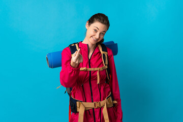 Young mountaineer woman over isolated blue background making money gesture