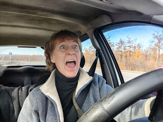 Terrified female driver a second before the accident. Scared middle-aged adult woman holds the steering wheel of a car. Frightened Lady girl who is owner or rent a car for travel