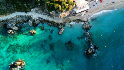 Drone aerial beach view over turquoise crystal clear water, rocky coastline at Greek island's paradise
