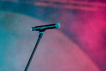 Isolated Microphone with stand on a concert stage with blurred stage lighting background