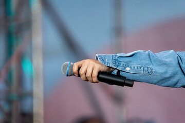 A hand holding a microphone on a stage