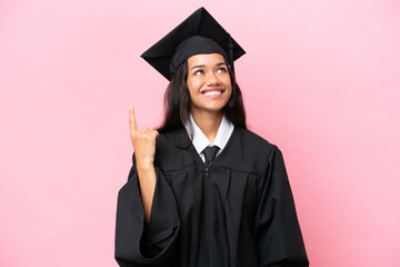 Young university Colombian woman graduate isolated on pink background pointing up and surprised