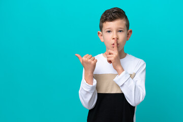 Little kid boy isolated on blue background pointing to the side and doing silence gesture