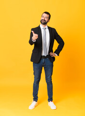 Full-length shot of business man over isolated yellow background shaking hands for closing a good...