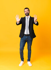 Fototapeta na wymiar Full-length shot of business man over isolated yellow background counting eight with fingers
